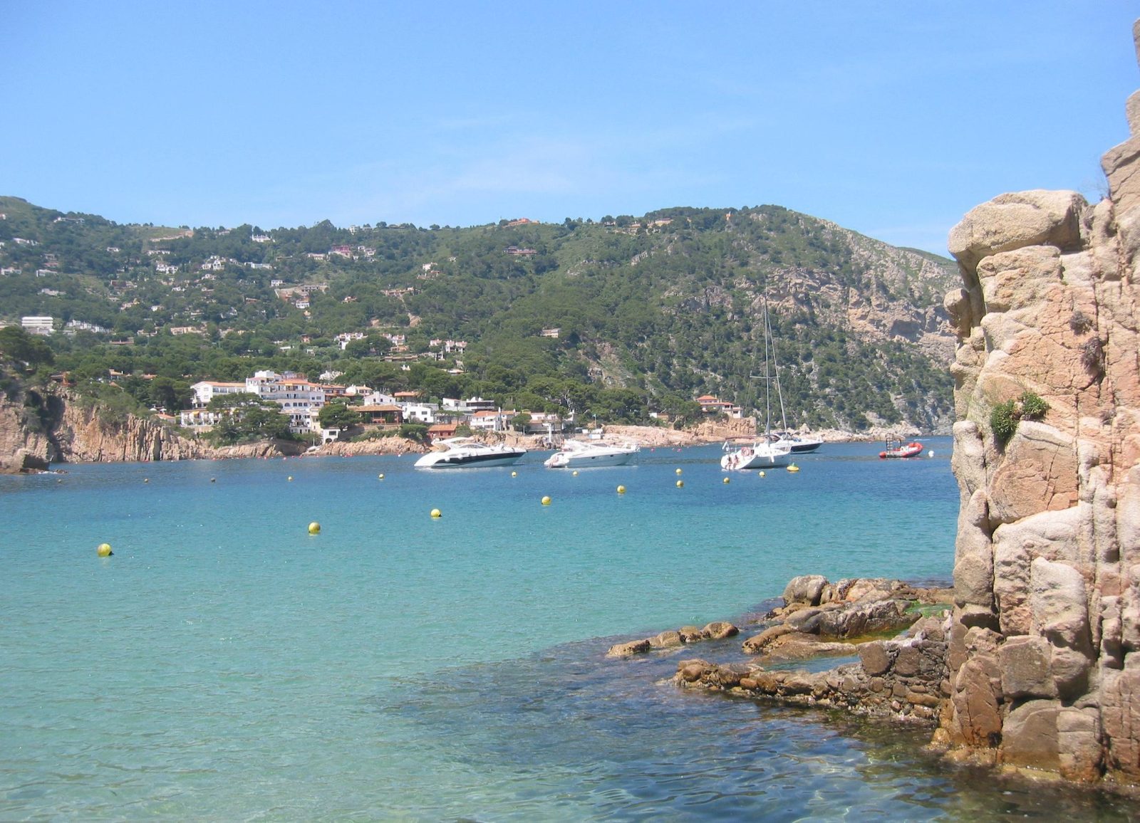 Bahía de Aiguablava en Begur, agua turquesa con barcas fondeadas y pinar sobre la roca