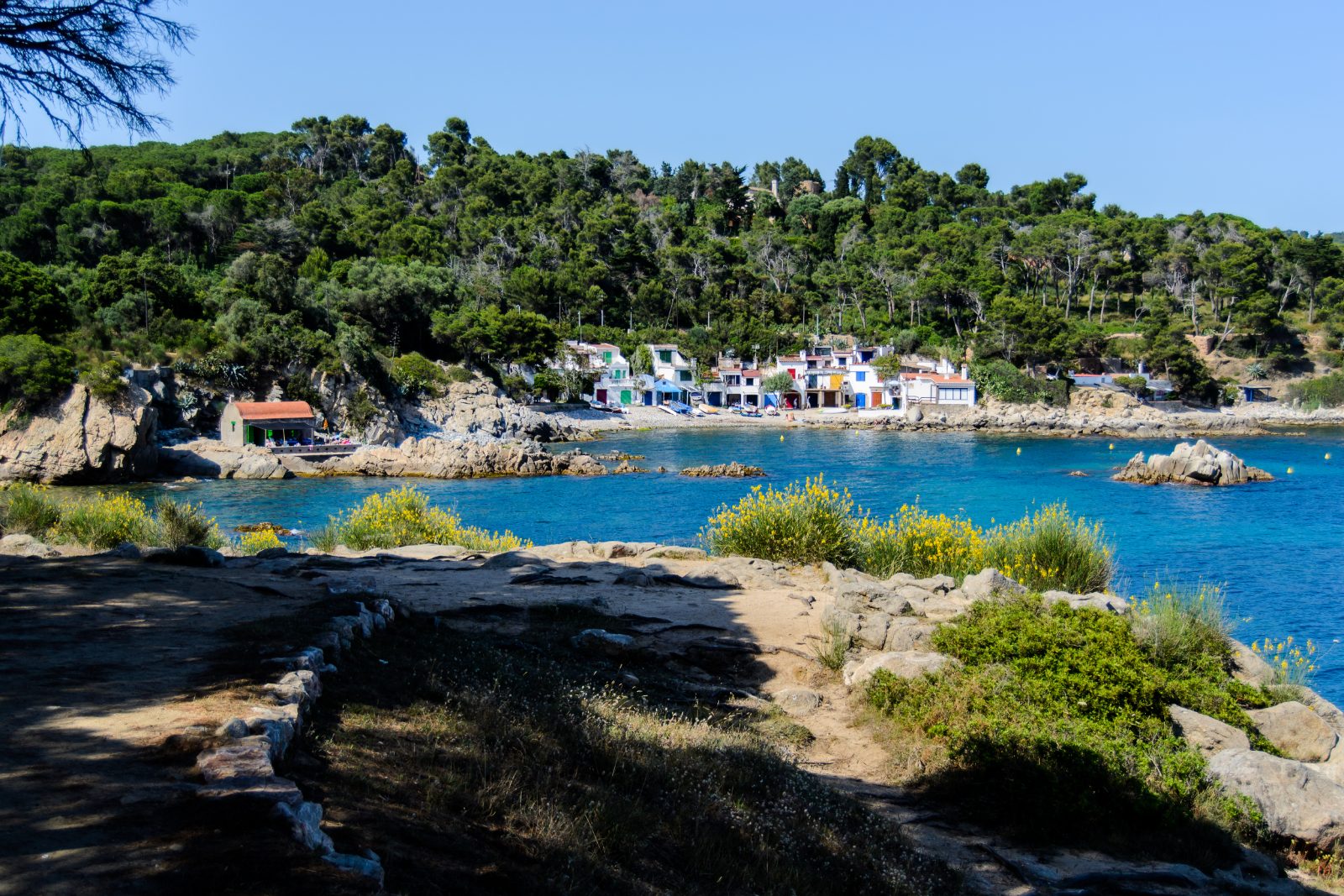 Cala S'Alguer en Palamós, barracas de pescadores de colores sobre agua turquesa